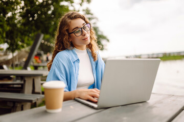 Portrait of beautiful woman working online using a laptop and enjoying the natural landscape...