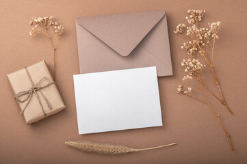 Brown envelope on a beige coffee background, craft gift box and dried gypsophila flowers. Warm earthy tones.Greeting card.