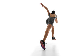 Sportive young woman, runner athlete in motion, training, running against white studio background. Dynamic image. Concept of sport, active and healthy lifestyle, sportswear, competition