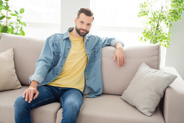 Photo portrait of brunet sitting on sofa wearing jeans outfit smiling chilling on holiday