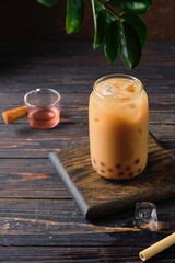 Cool drink, Taiwanese bubble tea with almond milk with tapioca balls in a glass glass on a dark wooden background. Refreshing soft drinks, cocktails.