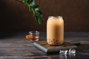 Cool drink, Taiwanese bubble tea with almond milk with tapioca balls in a glass glass on a dark wooden background. Refreshing soft drinks, cocktails.
