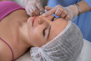 Expert hands perform an injection, a crucial step in the client's beauty regimen. It's a fusion of...