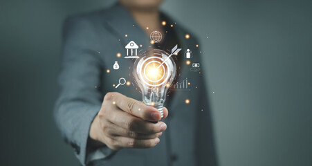 Business Innovation and Strategy Concept with Light Bulb Business professional showcasing a light bulb with glowing icons related to finance, strategy, and global business concepts.