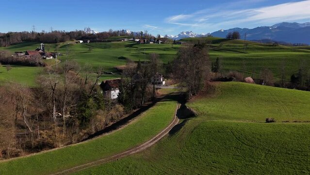Lush green fields in jona with glarus alps in the background, clear sky, aerial view