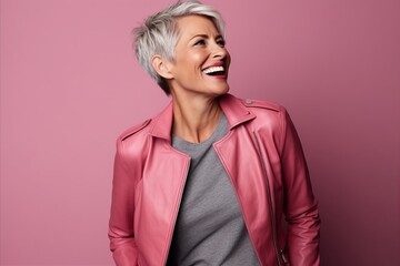 Portrait of a happy mature woman in pink leather jacket on pink background
