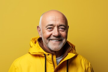 Portrait of an elderly man in a yellow jacket on a yellow background