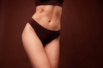 Fotobehang Cropped unfiltered natural photo of slim gorgeous girl thin legs fit stomach dressed underwear isolated on dark brown color background © deagreez