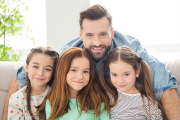 Obraz premium Portrait of four persons handsome guy hugging adorable positive girls look camera have good mood indoors