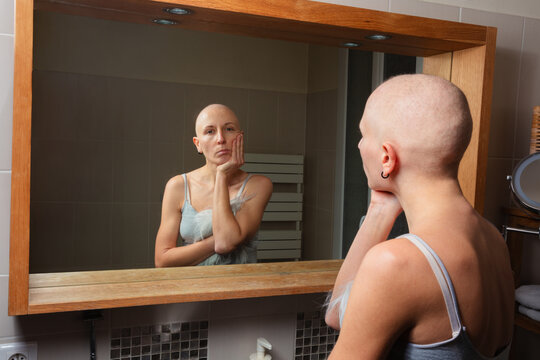 Individual struggle with cancer gazes at reflection, thoughtful