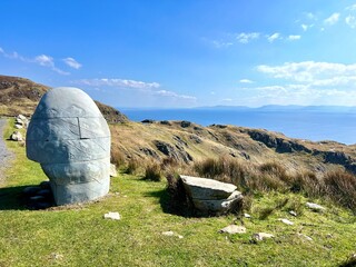 Rock sculpture near cliff with blue sky, ocean and green grass, Slieve League, County Donegal, Ireland 