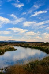 Wood River Wetland with blue sky, reflection in water and mountains in background, Chiloquin, Oregon