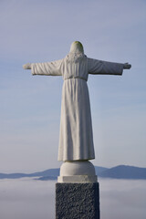 Statue on Santa Barbara Hill in Favaios with panoramic views above the clouds.