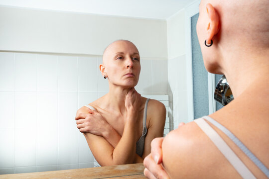 Contemplating woman ill of cancer facing her image without hair