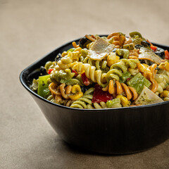 Cold pasta salad dish with chopped vegetables and sauce