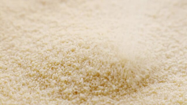 Uncooked couscous grains falling down close up