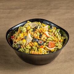 Cold pasta salad dish with chopped vegetables and sauce