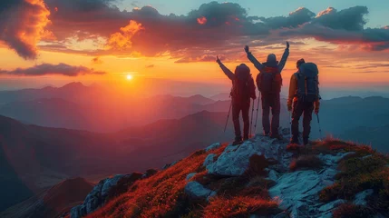 Tuinposter A group of hikers with backpacks raise their arms in triumph on a mountain summit as the sunset paints the sky with warm hues. Friendship successful target achievement unity concept. © Davin