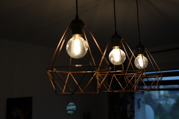 Three pendant lamps in the room. Design lighting solution. Geometric chandeliers. Crystal chandelier shape.