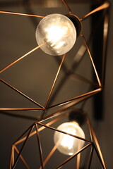 Element of a room chandelier. Compact pendant lamp with diamond shape. Geometric shape of the chandelier. The light bulb is on.