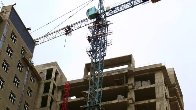 High tower crane for house building at the construction site on blue sky background