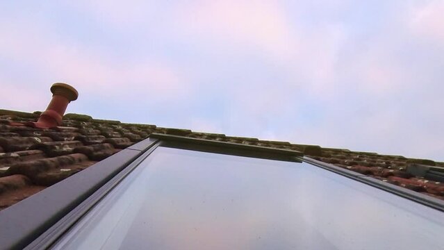 Dachfenster mit sich spiegelnden Wolken die Abends im Zeitraffer vorbeiziehen, rote Ziegel, Dachd&auml;mmung
