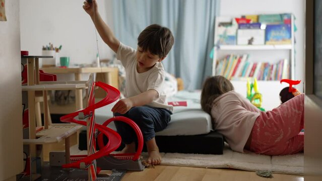 Children playing in bedroom, candid little brother and sister engaged in imaginative play at home, childhood leisure activity