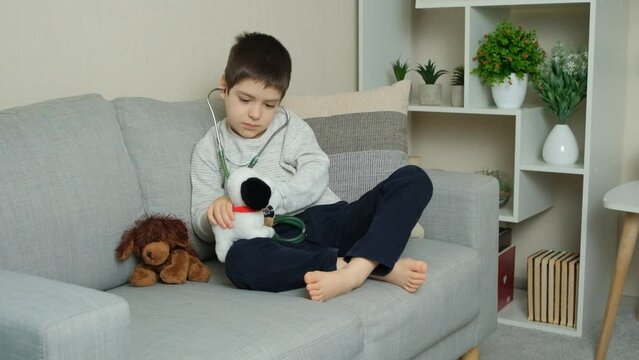 Little kid doctor listening to toy plush dog with stethoscope