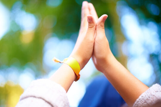 Outdoor, closeup and people with high five, nature and agreement with bokeh background or fresh air. Fun, closeup or friends with hand gesture or support with party or event with motivation or ribbon