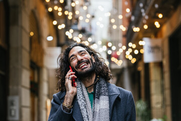 Man smiling while talking on the phone outdoors.