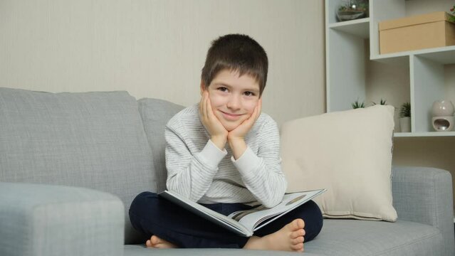 Cute 6 year old child flipping through a book, looking at pictures and learning to read.
