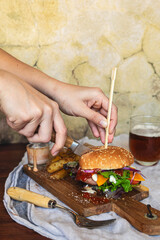 A hand cutting an exquisite gourmet hamburger. Irresistible flavors, unhealthy fast food concept.
