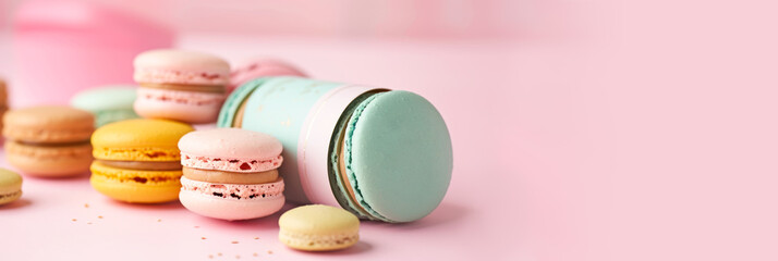 Sweet colorful macarons banner for cafe, confectionery, pastry shop. Copy space. Delicious French macaroons on trendy pastel peachy background. Macarons sale, offer, promotion