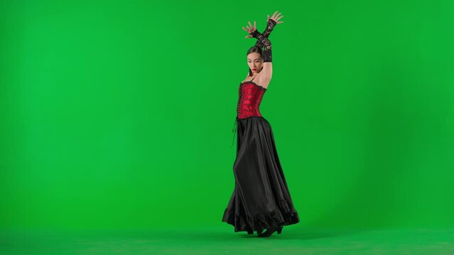 Woman dancer dancing on chroma key green screen. Female in flamenco style dress performs elegant spanish dance moves with her hands and body in the studio.