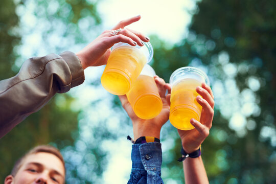Friends, beer and toasting in nature for celebration, bonding and unity in Canada from low angle. Group of people, hands and cups with alcohol for fun, entertainment and enjoyment outdoors in forest