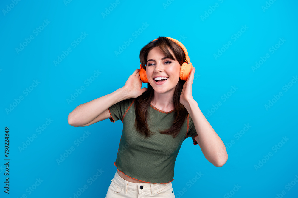 Sticker portrait of positive satisfied girl toothy smile hands touch headphones chilling isolated on blue co