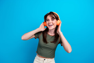 Obraz na płótnie Canvas Portrait of positive satisfied girl toothy smile hands touch headphones chilling isolated on blue color background
