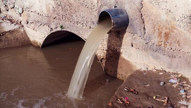 Wastewater sewage pipe dumps the dirty contaminated water into the river. Water pollution, environment contamination concept