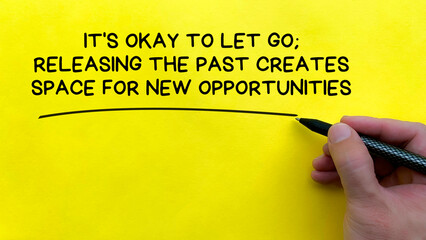 Hand writing It is okay to let go affirmation on yellow cover background. Affirmation concept.