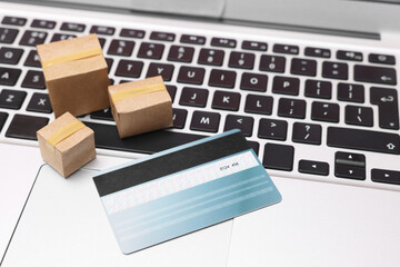 Internet shopping. Small cardboard boxes and credit card on laptop, closeup