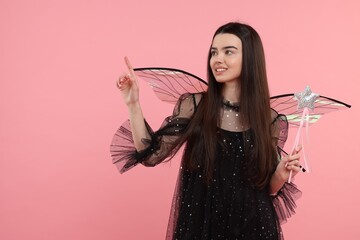 Beautiful girl in fairy costume with wings and magic wand on pink background. Space for text