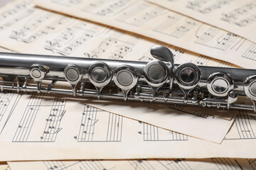 Classical flute on sheets with musical notes, closeup