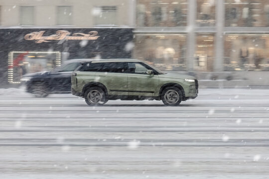 Jaecoo J7 SUV car on the city road during blizzard. Fast moving vehicle on winter streets. Compliance with speed limits on the road