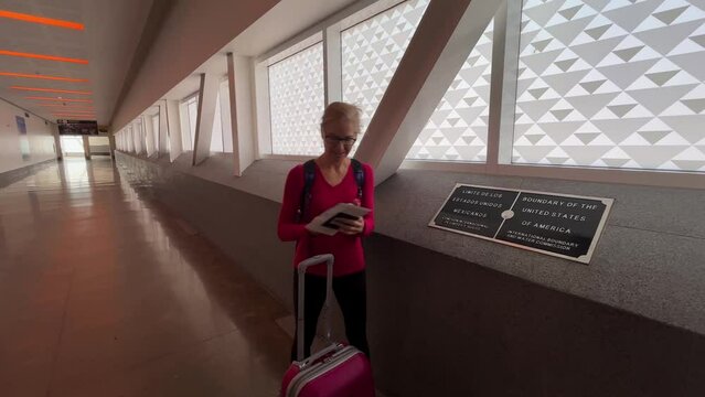 Woman taking a selfie of her in front of the Mexico USA border in the Cross Border Xpress bridge linking San Diego with Tijuana airport.
