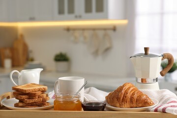 Breakfast served in kitchen. Toasts, honey, jam, fresh croissant, coffee and pitcher of milk in...