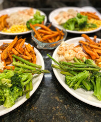 Home cooked dinner of broccoli, fries and shrimp on four plates