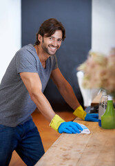 Happy man, portrait and cleaning table for housekeeping, hygiene or disinfection on furniture or surface at home. Male person, maid or cleaner and gloves for wiping, bacteria or germ removal at house