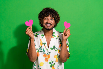 Photo of funky positive latin guy dressed print shirt showing two pink heart postcards isolated...