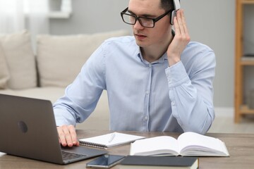 E-learning. Young man using laptop during online lesson at table indoors.