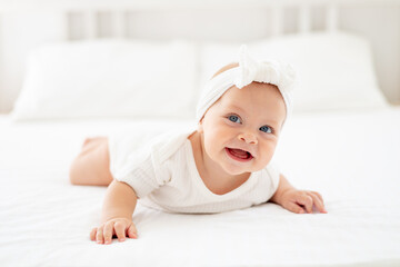smiling baby girl with blue eyes portrait close-up, happy little baby of six months lying on her...